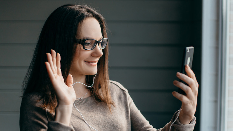 Waving and smiling at smartphone for video call