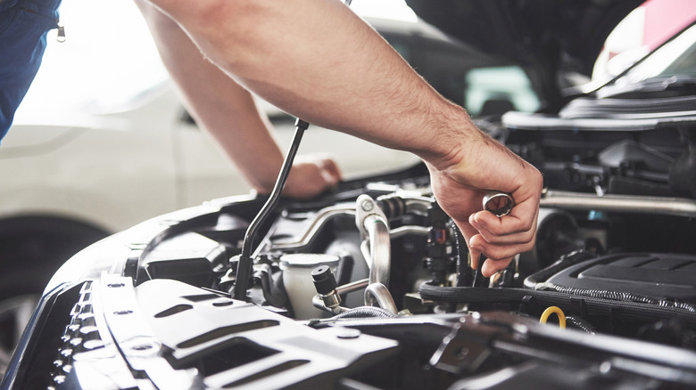 Close-up of person performing engine work on vehicle.