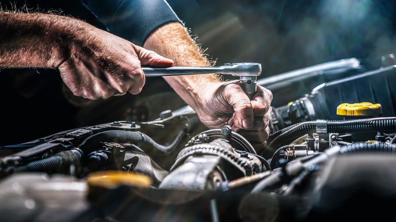 Close-up of mechanic working on car engine.