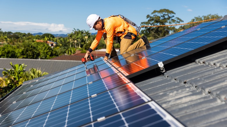 Technician installing solar panels on a roof