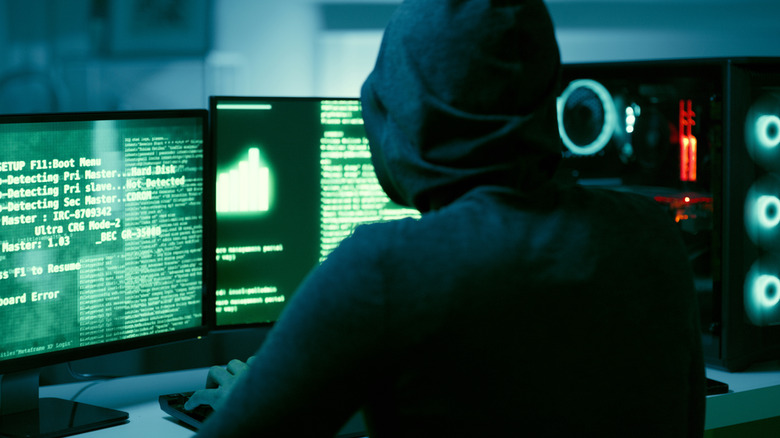 Cyber criminal dressed in black manipulating computer system
