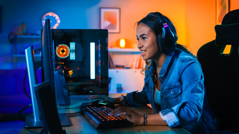 A girl playing a game on a PC wearing a headset