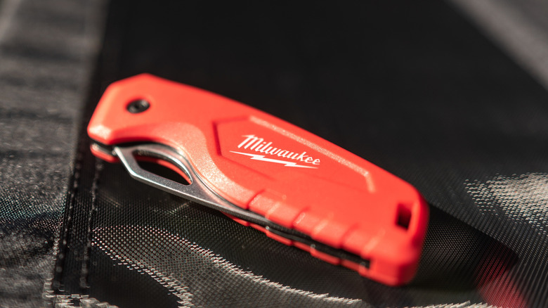 Person using a Milwaukee Utility Knife on a roofing shingle