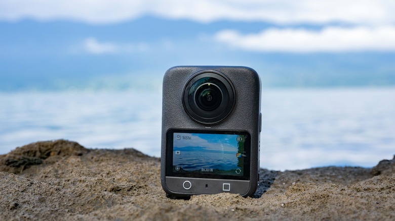 The DJI Osmo 360 sitting on a rock with a lack in the background.