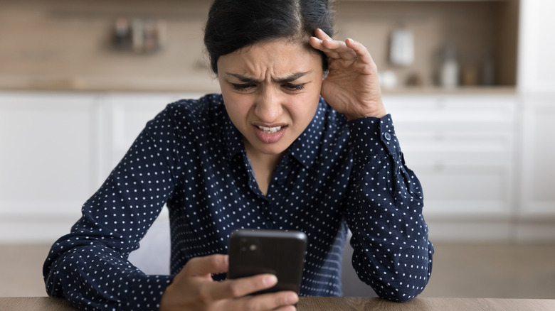 A girl looking nervous by looking at her phone.