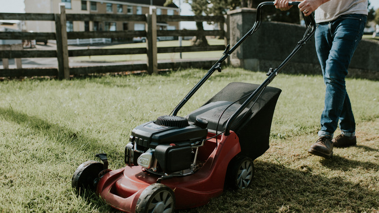 A man cutting grass in his lawn using a lawn mower