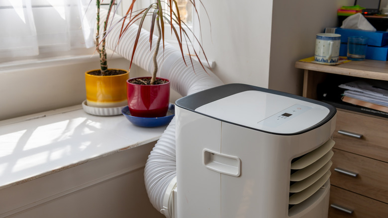A refrigerant-based portable air conditioner with hose venting outside through the window