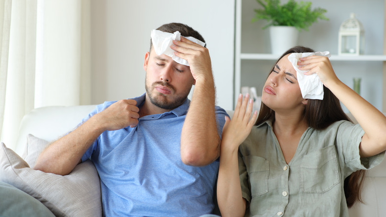 A man and woman visibly uncomfortable in a home during hot temperatures