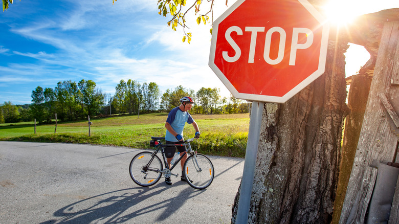 Cyclist stopped at rural intersection with stop sign in foreground