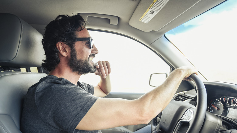 A man wearing sunglasses whille driving.