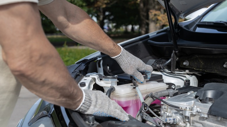 Man opening expansion tank to top up coolant