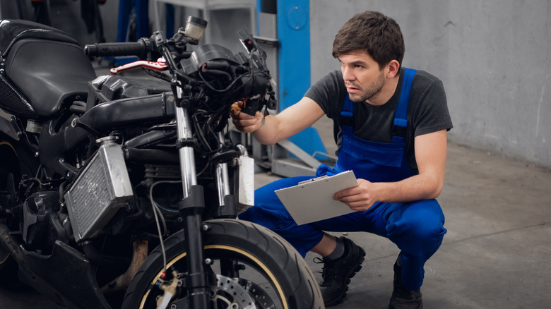 Inspector checking condition of old motorcycle