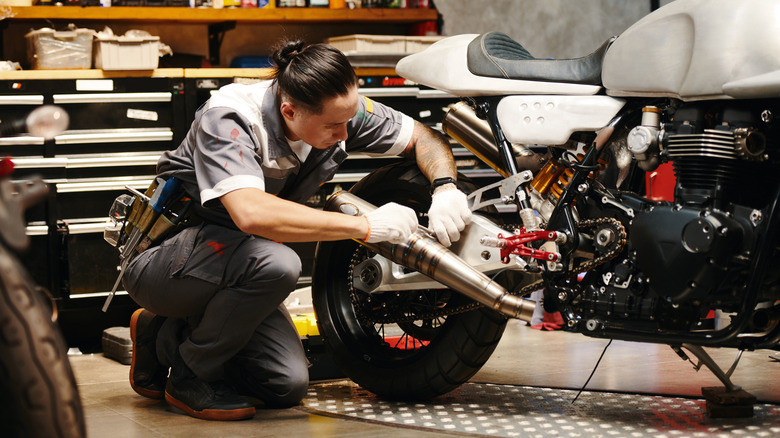 Man inspects exhaust system of motorcycle