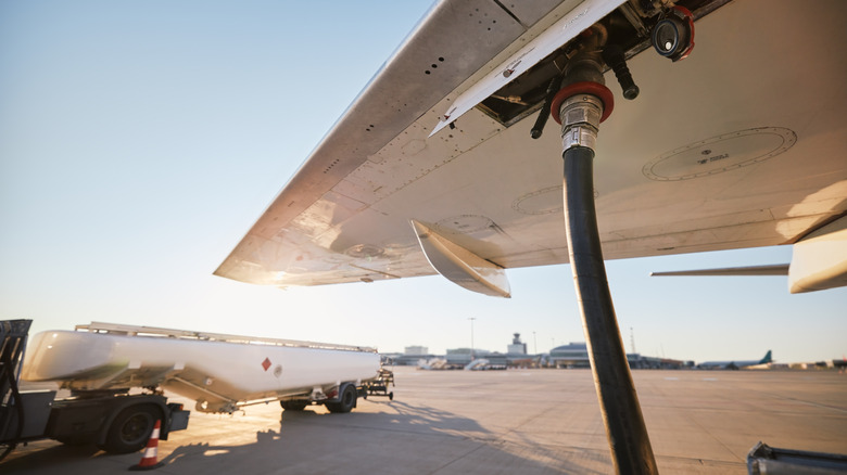 A fuel hose attached to an aircraft's wing during sunrise