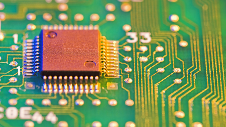 A close-up of a green and gold PC motherboard including a processing chip.