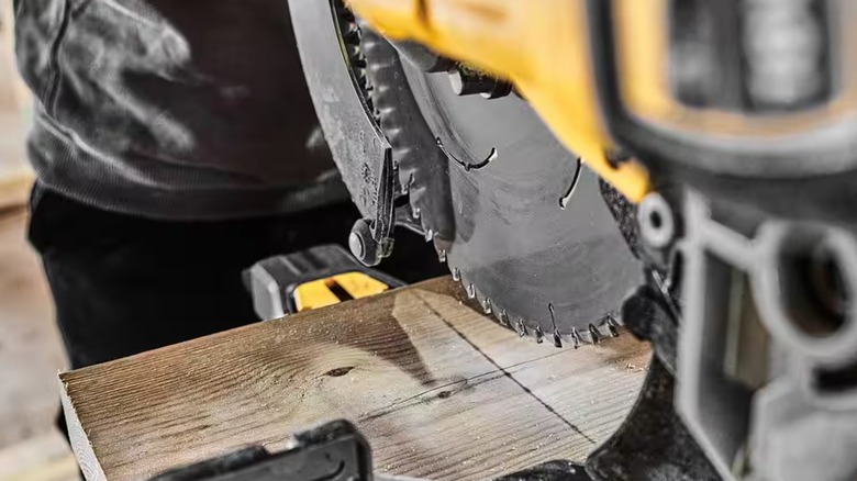 A DeWalt 60V miter saw creating a shadow line on a plank.