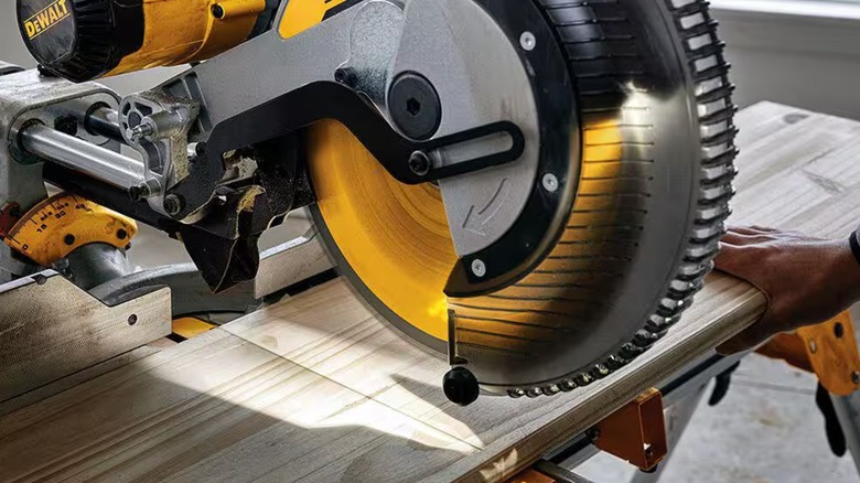 Running a DeWalt miter saw with an LED worklight creating a shadow line on a plank.