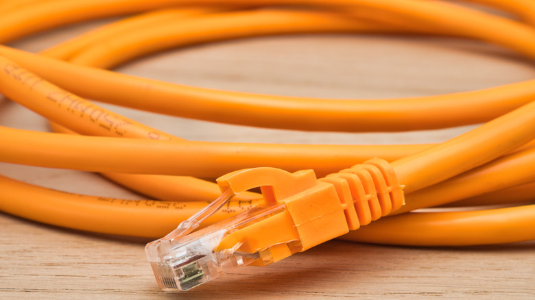 orange ethernet cable with an RJ45 connector placed on a wooden surface