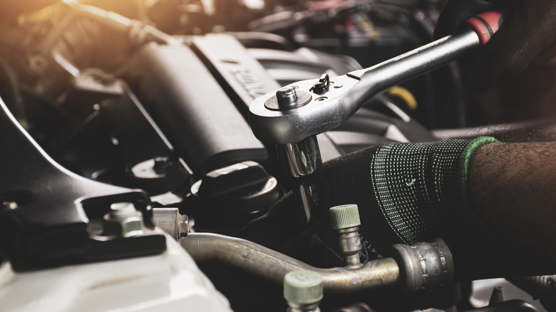 Man using socket wrench on engine