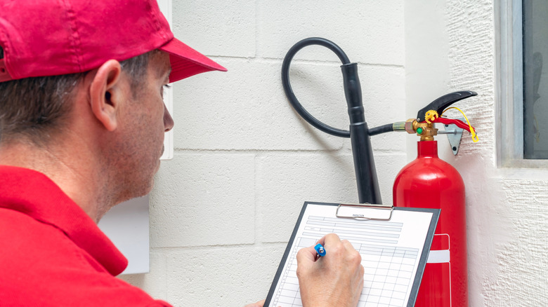 Person inspecting a fire extinguisher inside a building.