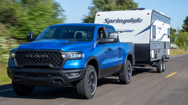 A bright blue Ram 1500 Rebel towing a camper