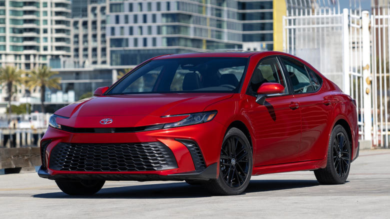 Red Toyota Camry SE parked in front of city skyline.