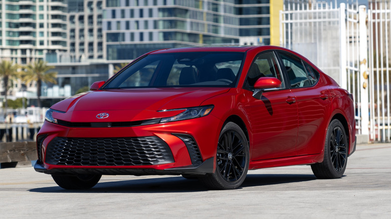 Red Toyota Camry SE parked in front of city skyline.