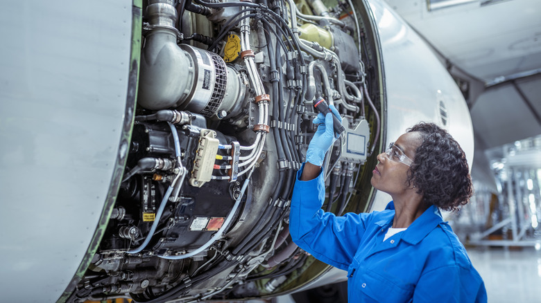 aircraft maintenance engineer inspects jet engine