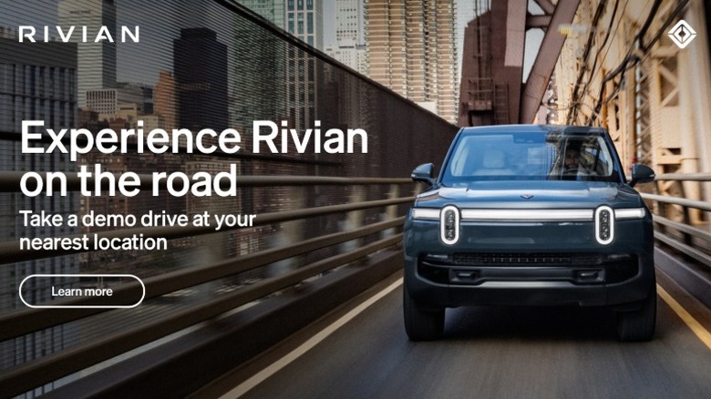 Blue Rivian EV vehicle driving in a city with text "Experience Rivian on the Road"