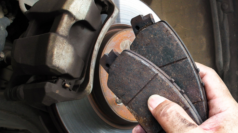 A person holding brake pads near a brake rotor