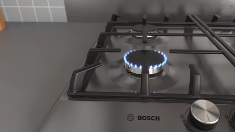Close up of a lit gas cooktop burner.