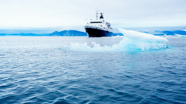 A ship at sea near a floating iceberg