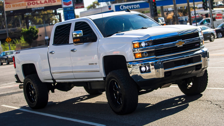 A lifted white Chevrolet Silverado truck in a parking space.