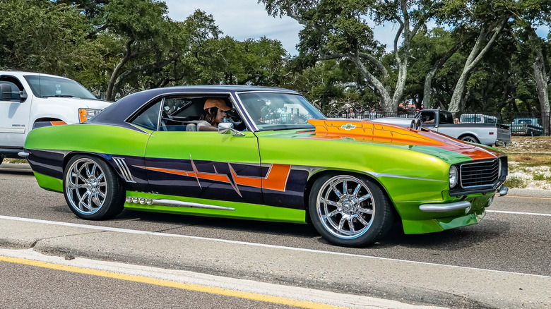 A highly modified multi-color Chevrolet Camaro driving on the road.