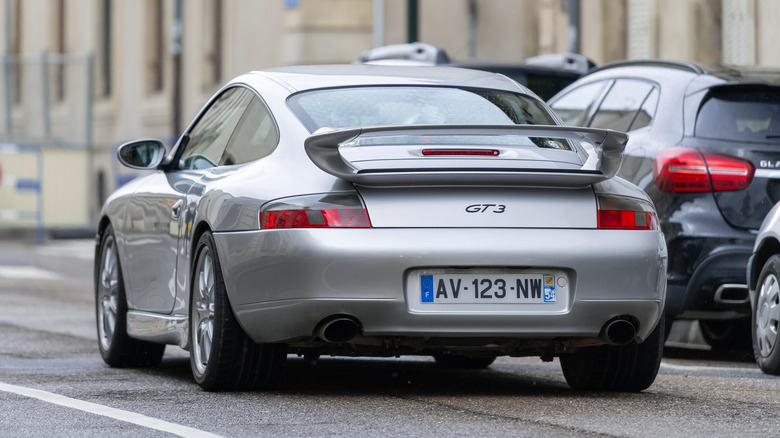 A silver Porsche 911 GT 3 driving on French city roads.