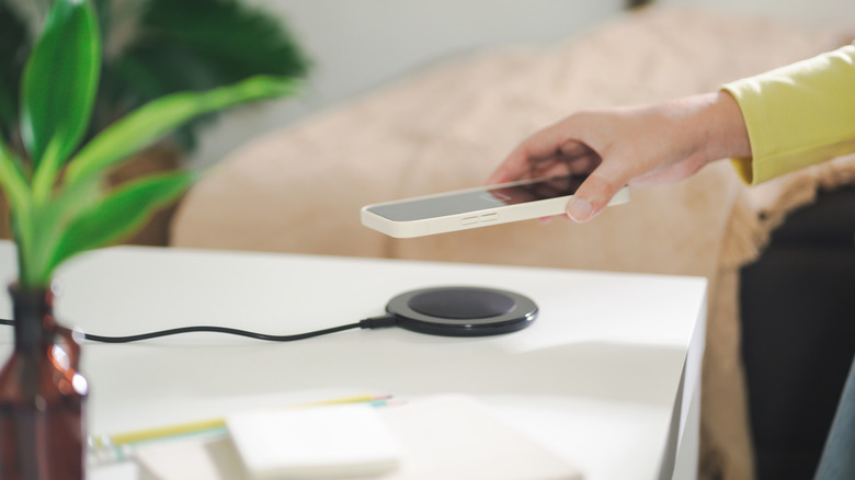 Hand placing phone with phone case on wireless charger