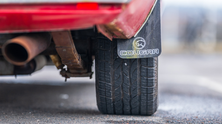 Rear tire exhaust and Cougar mudflap detail on vintage American muscle car