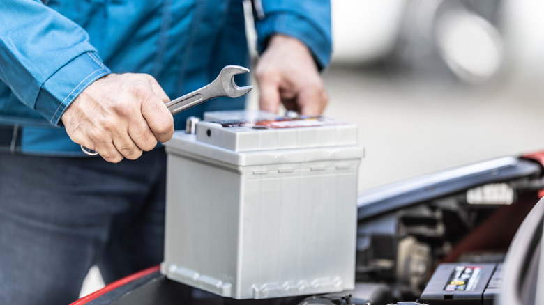 A mechanic holding a car battery to check its charge