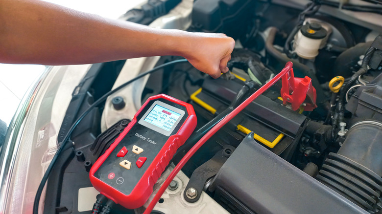 A car mechanic testing the battery with digital electronic battery tester