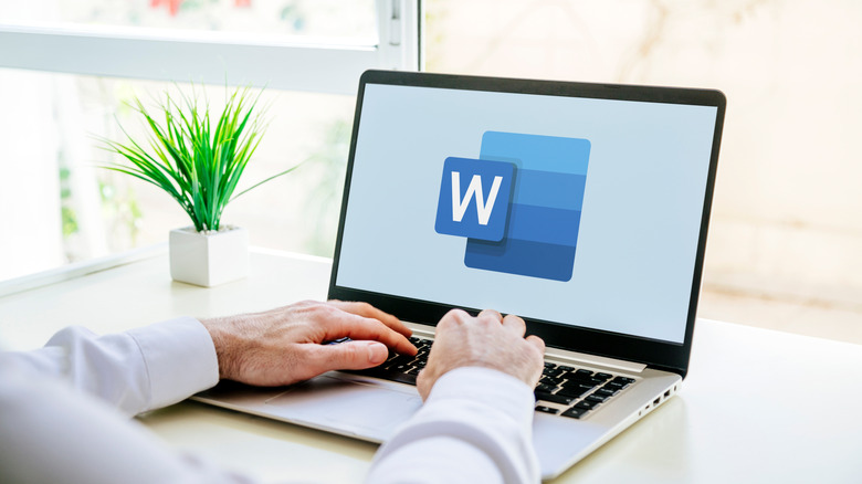 Man typing on laptop with Word logo displayed