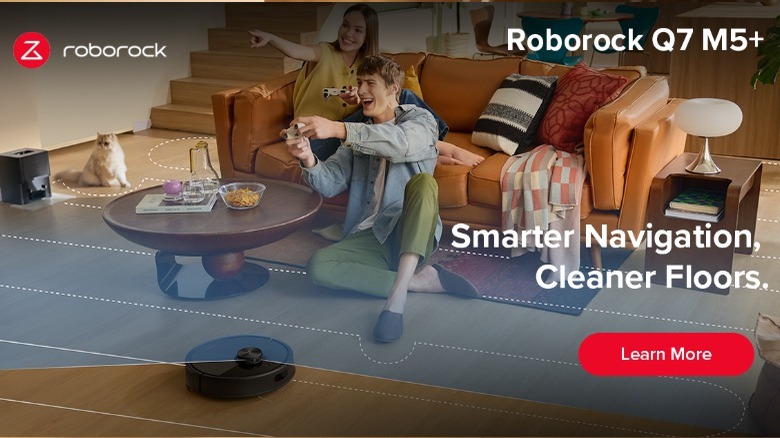 Roborock black Q7 M5+ robot vacuum in home with couple gaming on couch