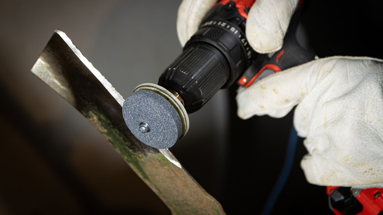 A person sharpening lawn mower blades