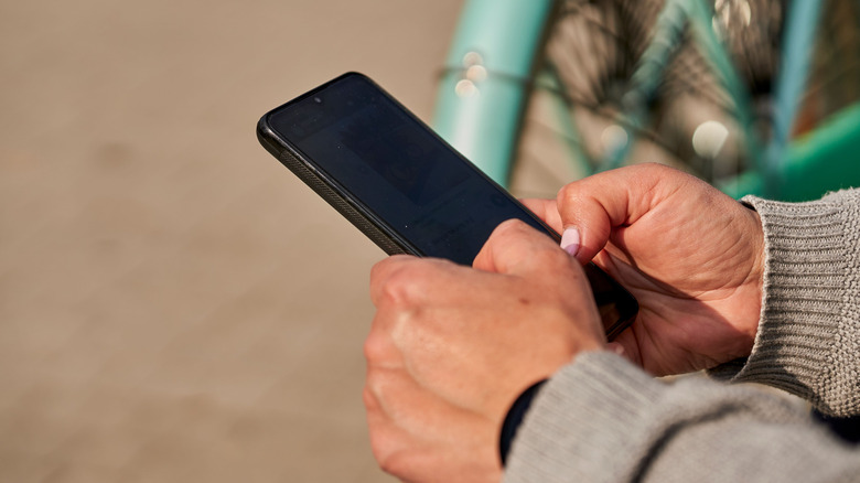 Person using phone with dark screen
