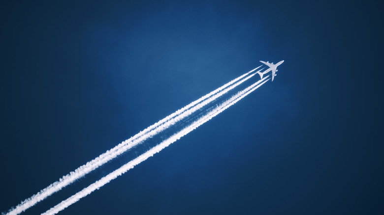 Airplane flying at high speeds, leaving behind smoke trails