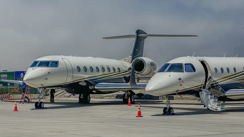 2 white private jets parked on an airport