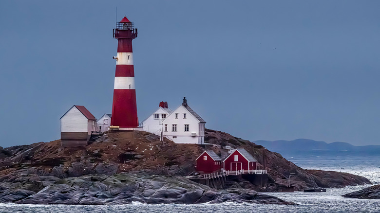 A red and white lighthouse on a small island