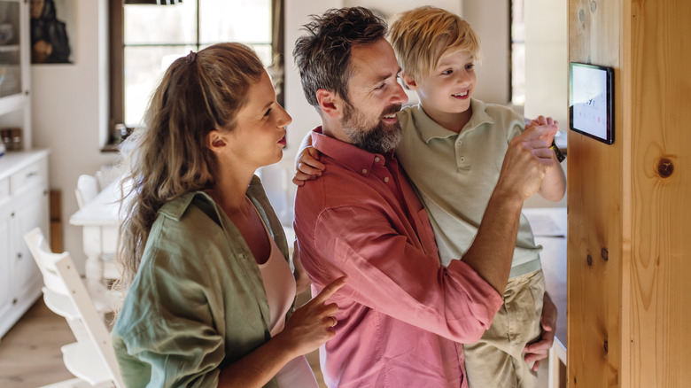 Family looking at smart thermostat and adjusting temperature
