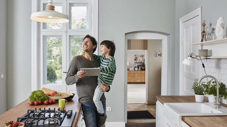 A man carrying his son looking at a smart bulb in their home
