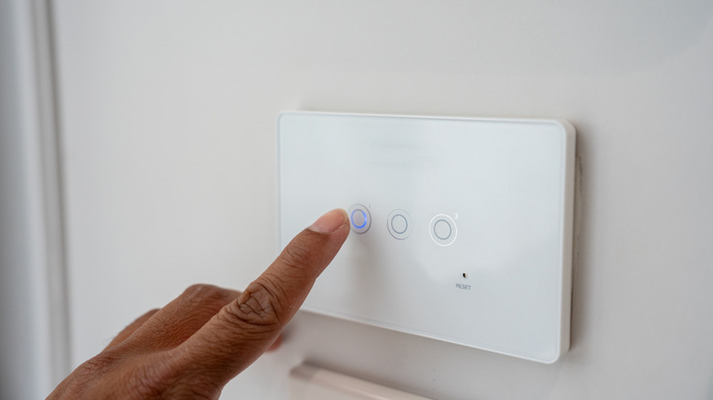 Person pressing button on home smart light switch panel