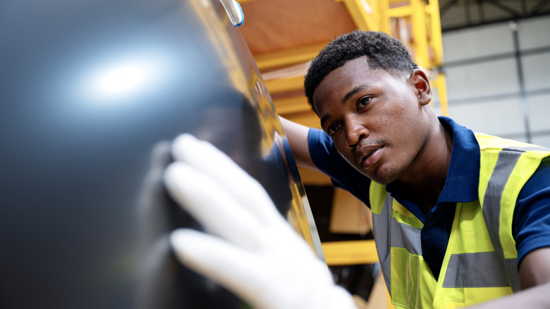 A mechanic inspecting a car's paint quality and finish